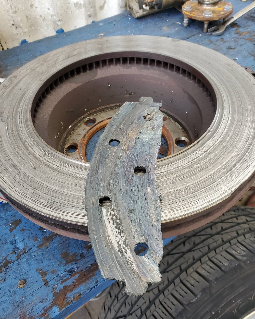 A worn brake rotor and pad shown to a customer