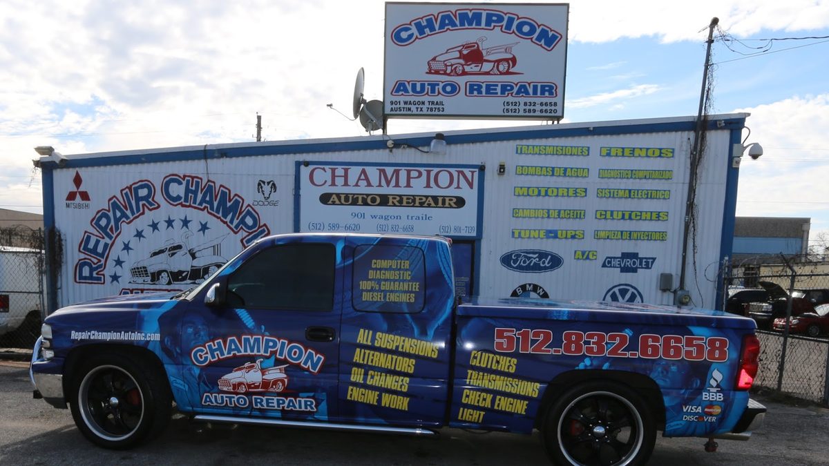 The Repair Champion Auto truck parked in front of the shop